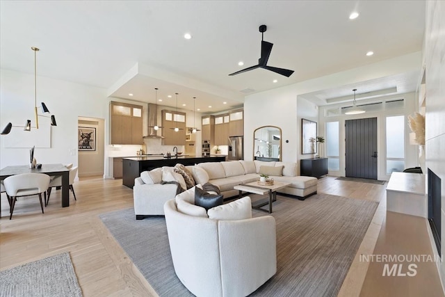 living room with light wood-type flooring, sink, and ceiling fan