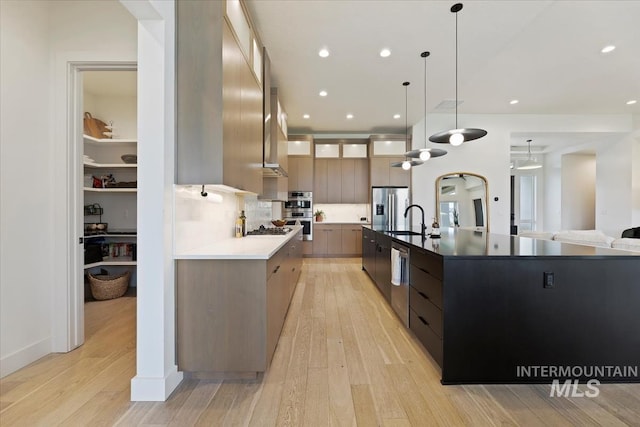 kitchen featuring a large island, stainless steel appliances, light hardwood / wood-style floors, and decorative light fixtures