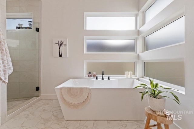 bathroom featuring plenty of natural light and separate shower and tub