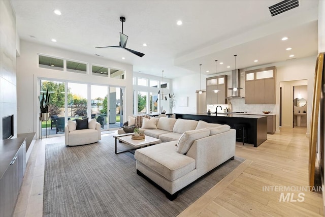 living room featuring light wood-type flooring, ceiling fan, and a healthy amount of sunlight