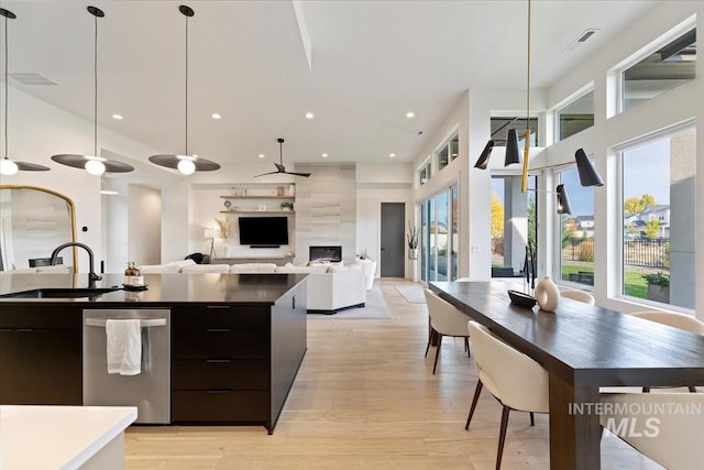 kitchen featuring hanging light fixtures, sink, light hardwood / wood-style flooring, and dishwasher