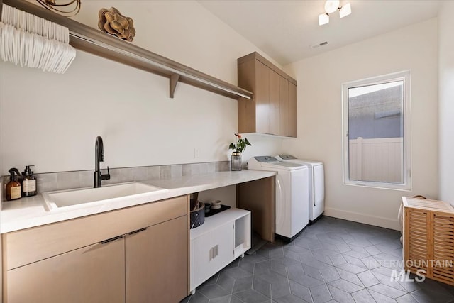 washroom featuring dark tile patterned flooring, washing machine and dryer, cabinets, and sink