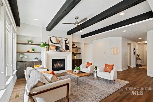 living room featuring beamed ceiling, ceiling fan, dark hardwood / wood-style flooring, and built in features