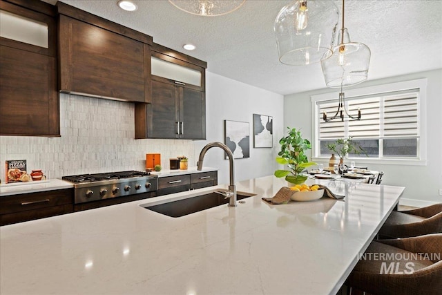 kitchen with sink, a breakfast bar area, light stone counters, a notable chandelier, and decorative backsplash