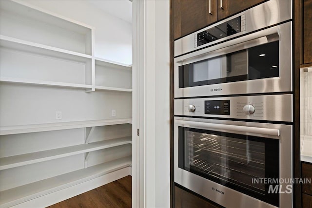 kitchen featuring dark wood-type flooring, dark brown cabinetry, and double oven