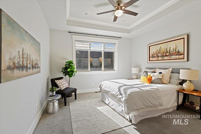 carpeted bedroom featuring ceiling fan and a raised ceiling