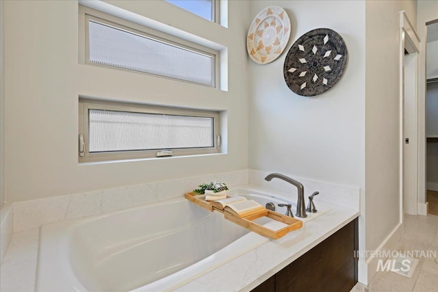 bathroom featuring tile patterned flooring and tiled bath