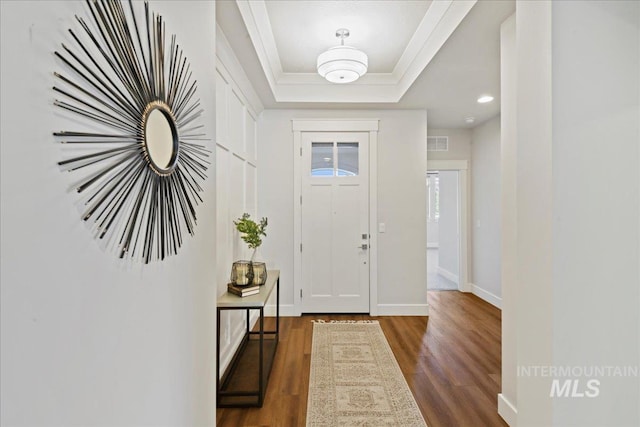 entrance foyer with crown molding, dark wood-type flooring, and a raised ceiling