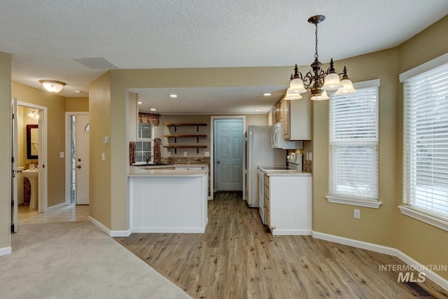 kitchen with stove, sink, hanging light fixtures, light wood-type flooring, and a notable chandelier