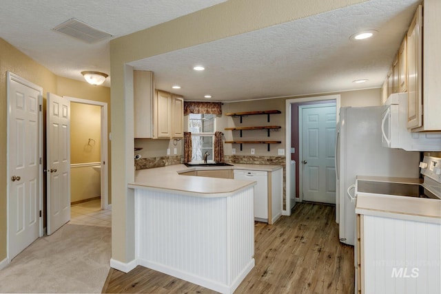 kitchen with kitchen peninsula, a textured ceiling, white appliances, sink, and light hardwood / wood-style floors