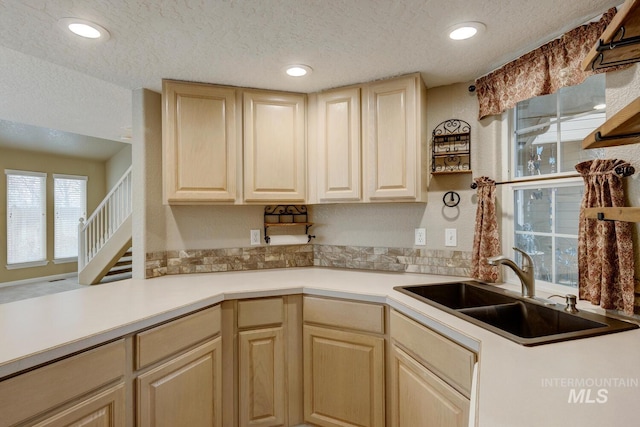 kitchen with kitchen peninsula, sink, a textured ceiling, and light brown cabinets