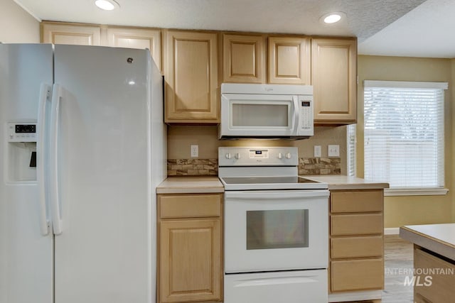 kitchen featuring a textured ceiling, light brown cabinets, and white appliances