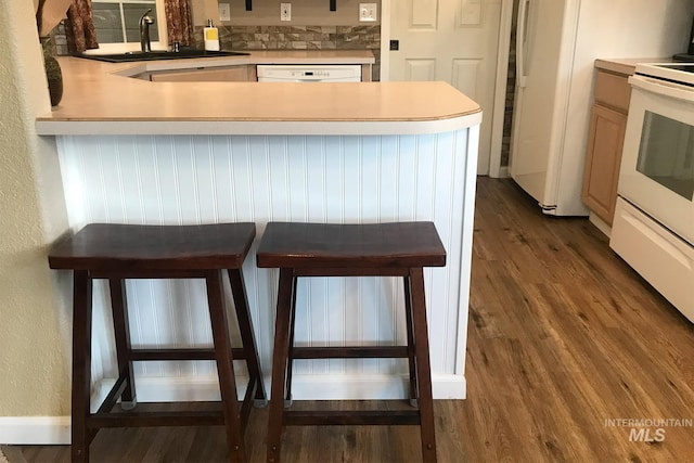 kitchen featuring kitchen peninsula, sink, dark hardwood / wood-style floors, and white appliances