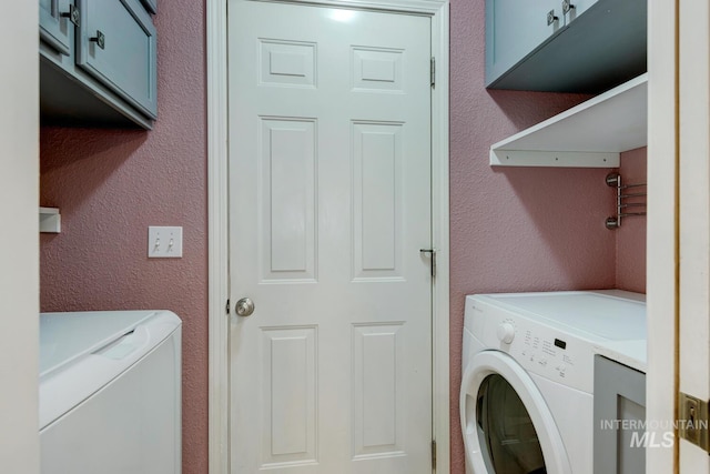 clothes washing area with cabinets and separate washer and dryer