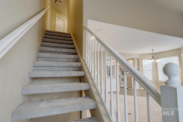 stairway featuring a chandelier