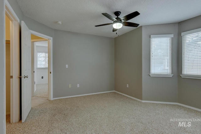 spare room with ceiling fan, light colored carpet, and a textured ceiling