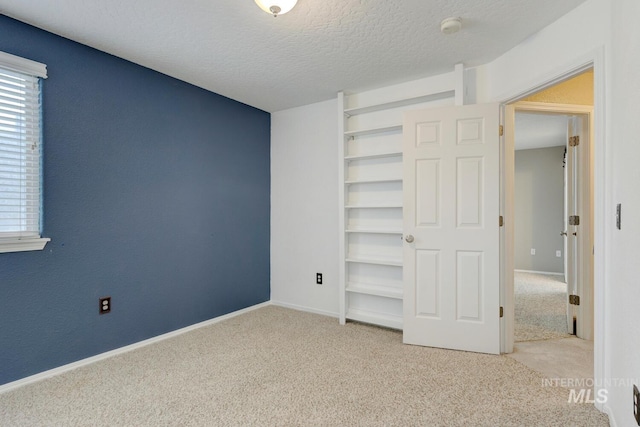 unfurnished bedroom with a textured ceiling and light carpet