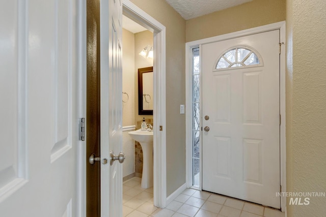 foyer entrance with light tile patterned floors and a textured ceiling