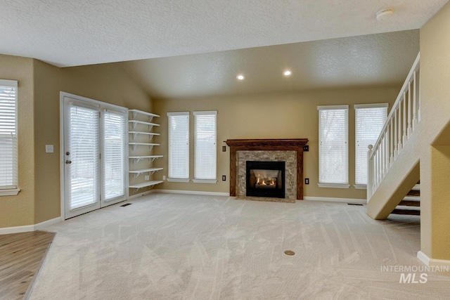 unfurnished living room with light carpet, a textured ceiling, and lofted ceiling