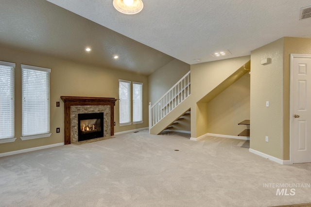 unfurnished living room with a textured ceiling, a fireplace, and light carpet