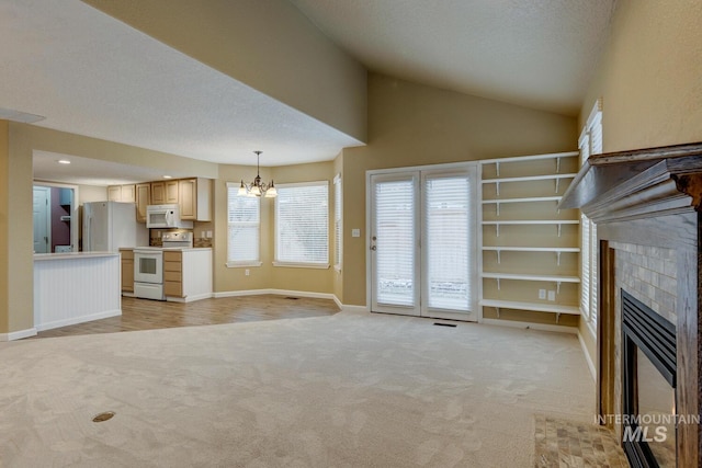 unfurnished living room with an inviting chandelier, a textured ceiling, vaulted ceiling, light carpet, and a fireplace