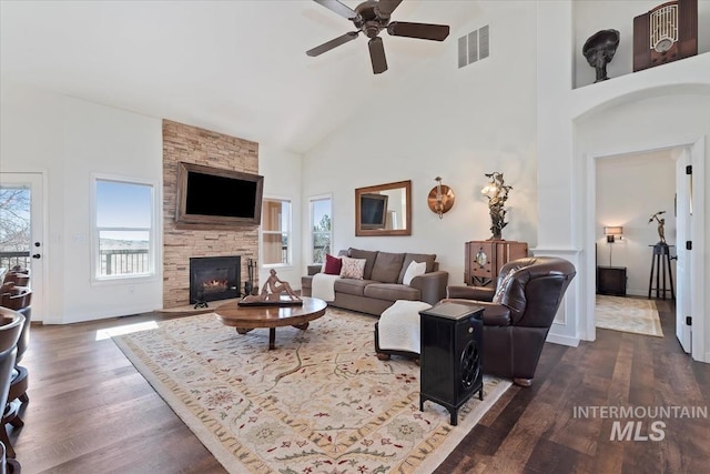 living room featuring visible vents, plenty of natural light, dark wood-type flooring, and high vaulted ceiling