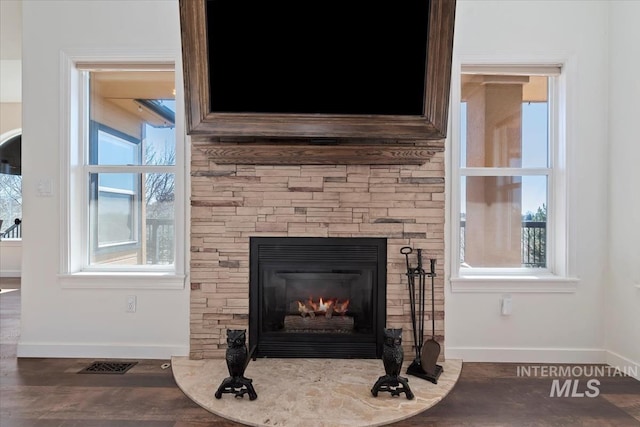 details featuring wood finished floors, a fireplace, visible vents, and baseboards