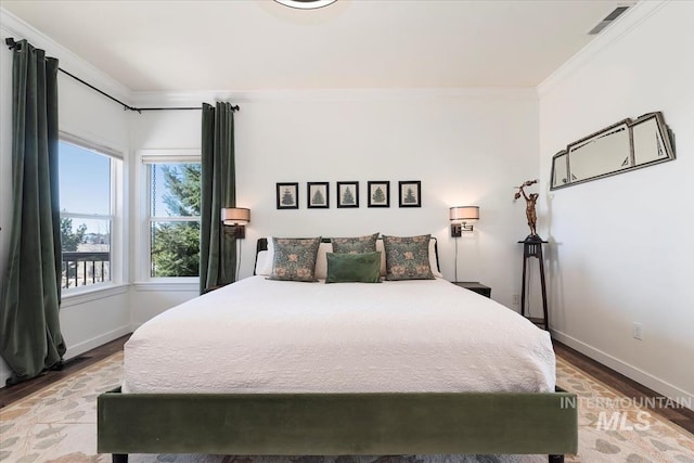 bedroom featuring visible vents, wood finished floors, baseboards, and ornamental molding