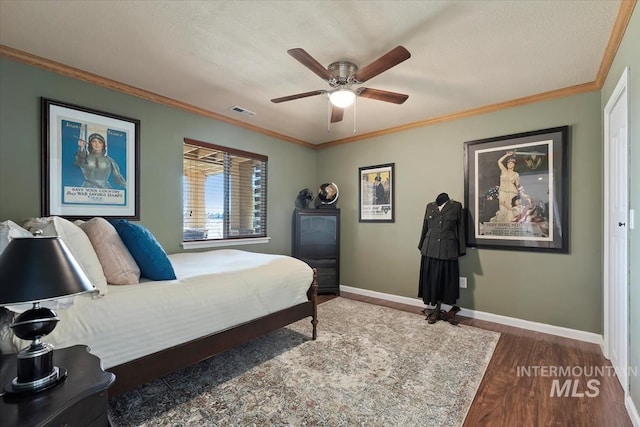 bedroom featuring visible vents, crown molding, baseboards, and wood finished floors