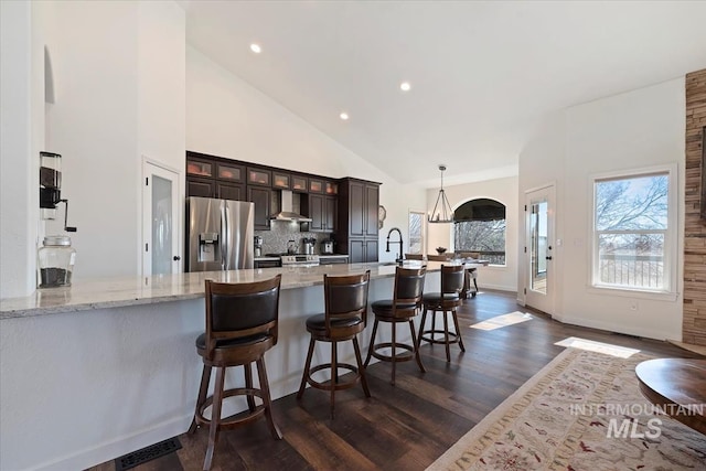 kitchen featuring glass insert cabinets, decorative backsplash, stainless steel refrigerator with ice dispenser, dark wood-style floors, and wall chimney exhaust hood