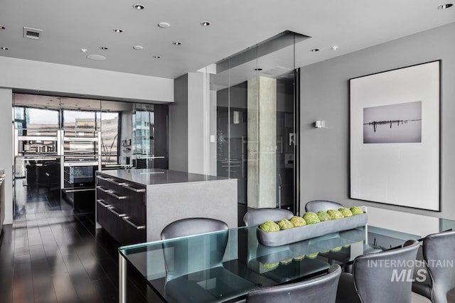 kitchen with modern cabinets, a center island, recessed lighting, multiple ovens, and dark cabinets