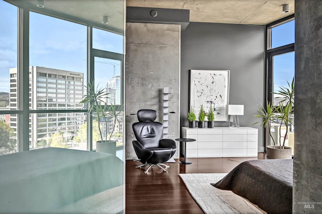 bedroom with wood finished floors, floor to ceiling windows, and a view of city