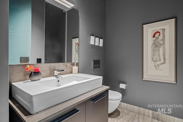 half bath with vanity, toilet, and baseboards
