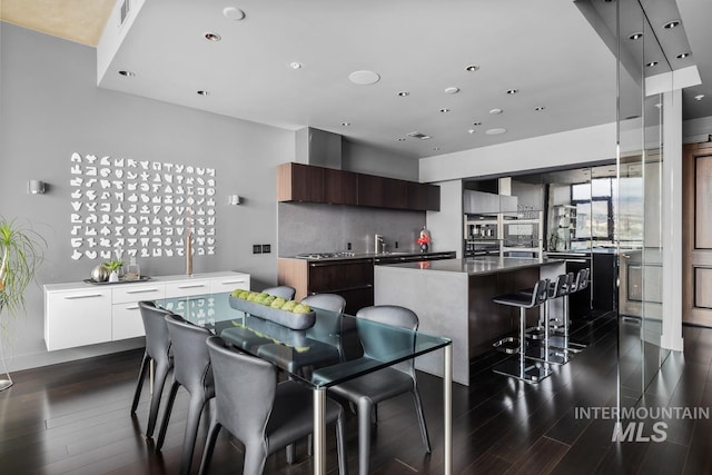 kitchen featuring modern cabinets, a center island, dark wood-style flooring, a breakfast bar area, and recessed lighting