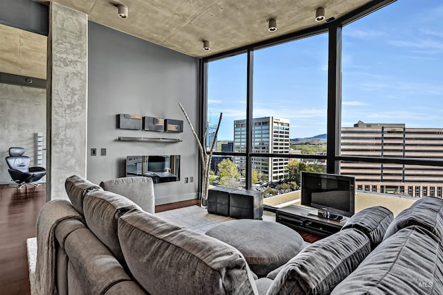 living area with a wall of windows, wood finished floors, and baseboards