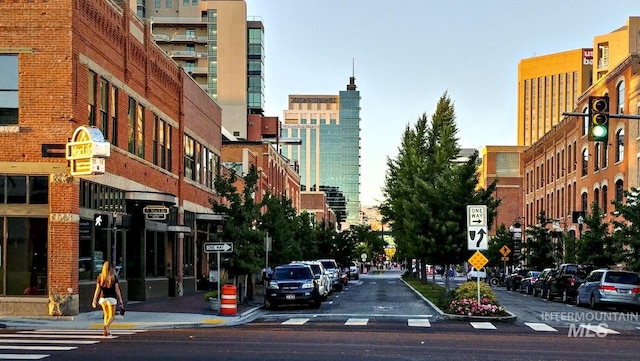 view of asphalt street with traffic signs, curbs, sidewalks, street lights, and a city view