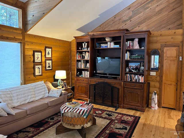 living room with wooden walls, high vaulted ceiling, and light wood-type flooring