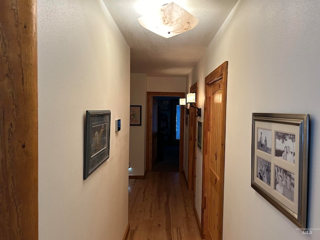 hall featuring a textured ceiling and hardwood / wood-style flooring