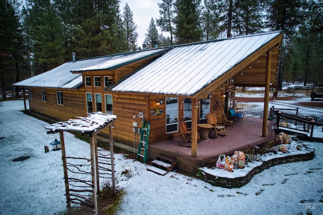 snow covered rear of property with a wooden deck