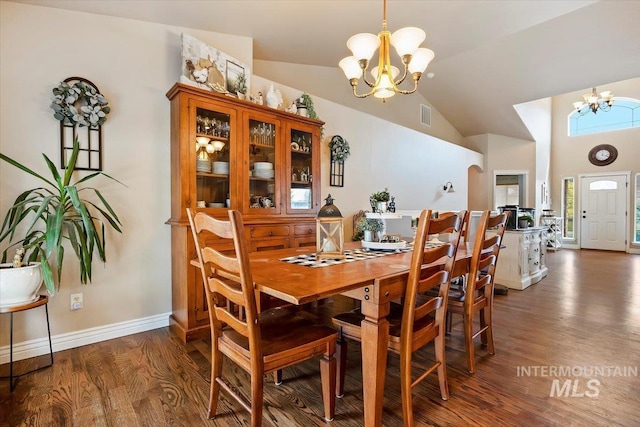 dining room with lofted ceiling, dark hardwood / wood-style flooring, and an inviting chandelier