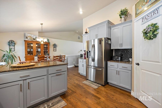 kitchen with gray cabinets, tasteful backsplash, dark stone counters, and stainless steel fridge