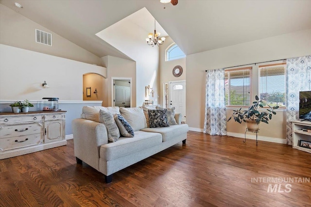 living room with high vaulted ceiling, an inviting chandelier, and dark hardwood / wood-style floors