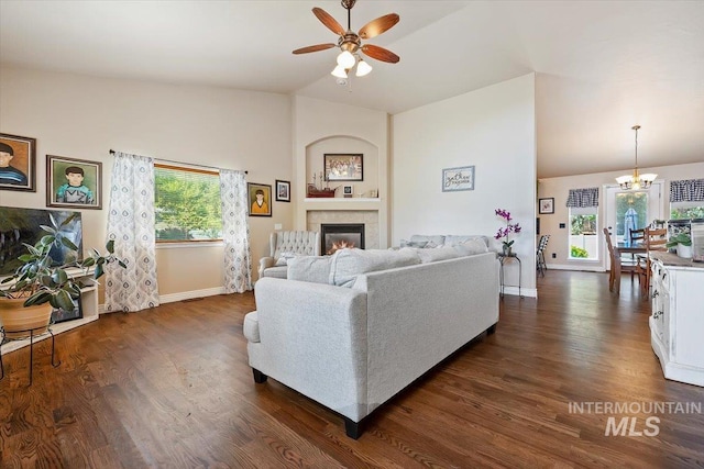 living room with ceiling fan with notable chandelier, vaulted ceiling, and dark hardwood / wood-style floors