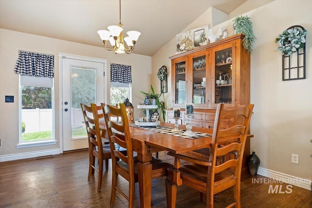 dining room with dark wood-type flooring, an inviting chandelier, and vaulted ceiling