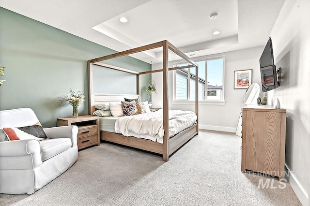 bedroom with baseboards, a tray ceiling, and light colored carpet