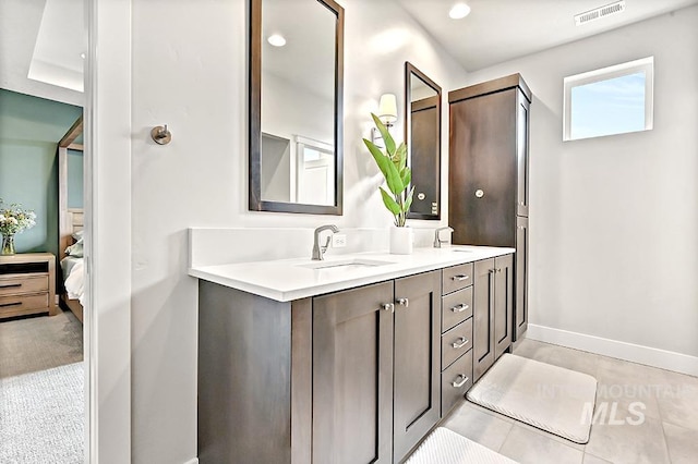 ensuite bathroom featuring double vanity, visible vents, a sink, baseboards, and connected bathroom