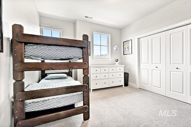 bedroom with visible vents, a closet, and light colored carpet