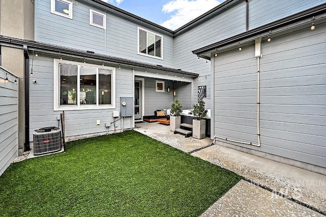 back of property featuring a yard and central AC