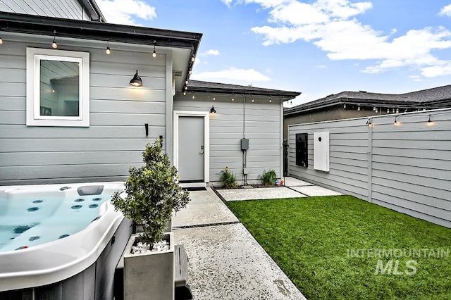 entrance to property with a hot tub, a yard, and fence