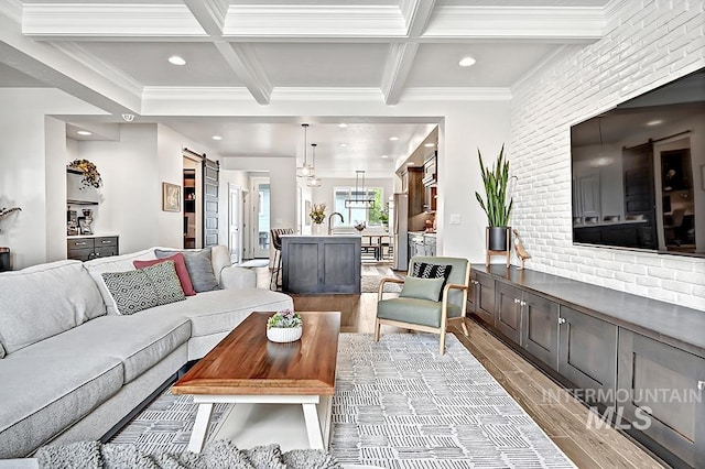 living room with a barn door, coffered ceiling, light wood-style flooring, and beamed ceiling
